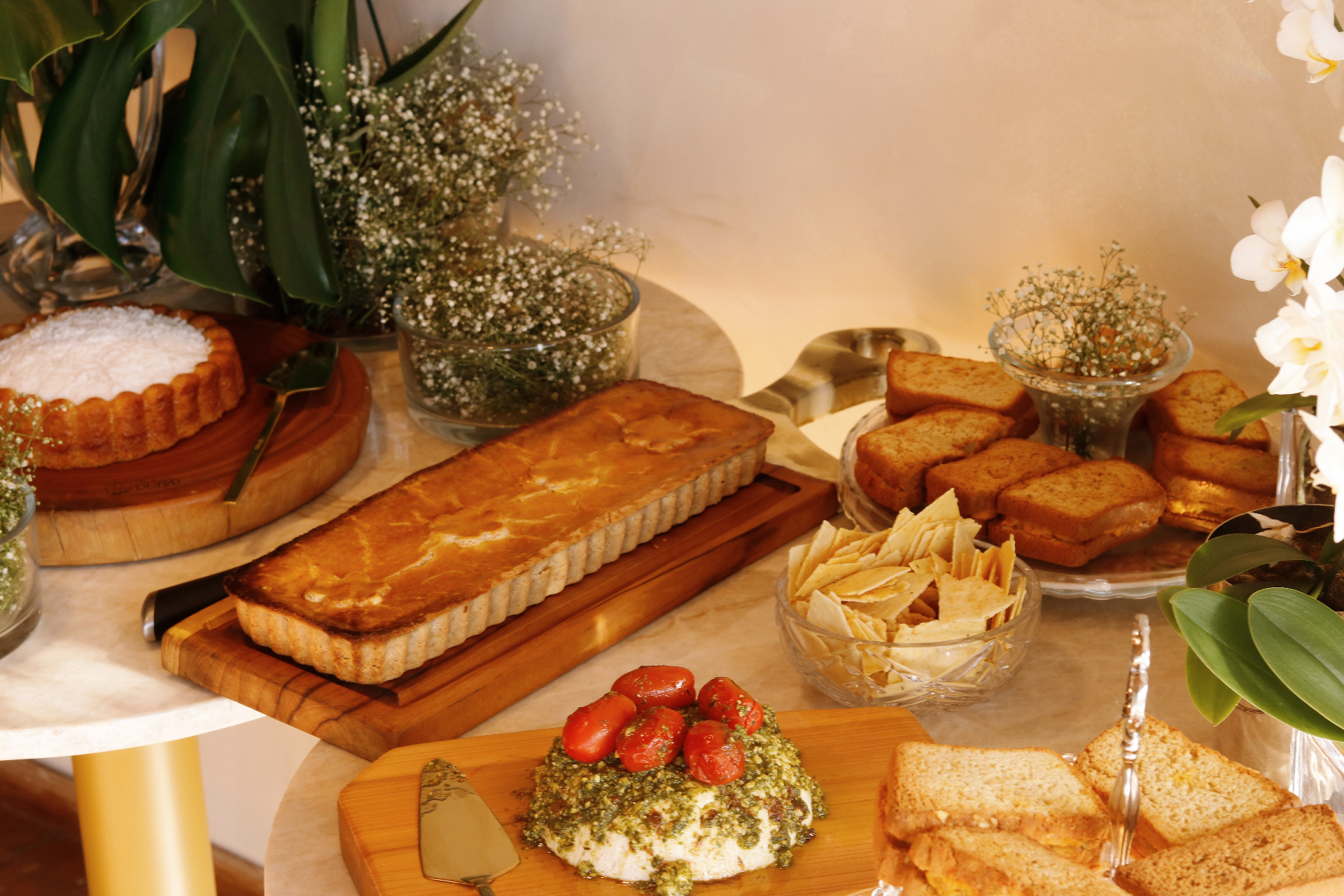 Mesa com quiche, pães, antepasto e salgados servidos em evento