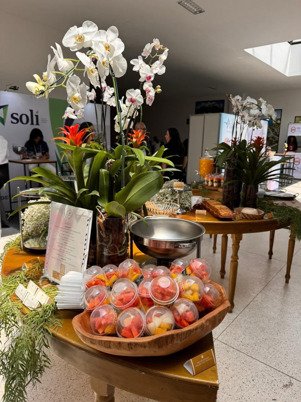 Mesa de congresso com frutas em potes individuais e buffet montado ao fundo