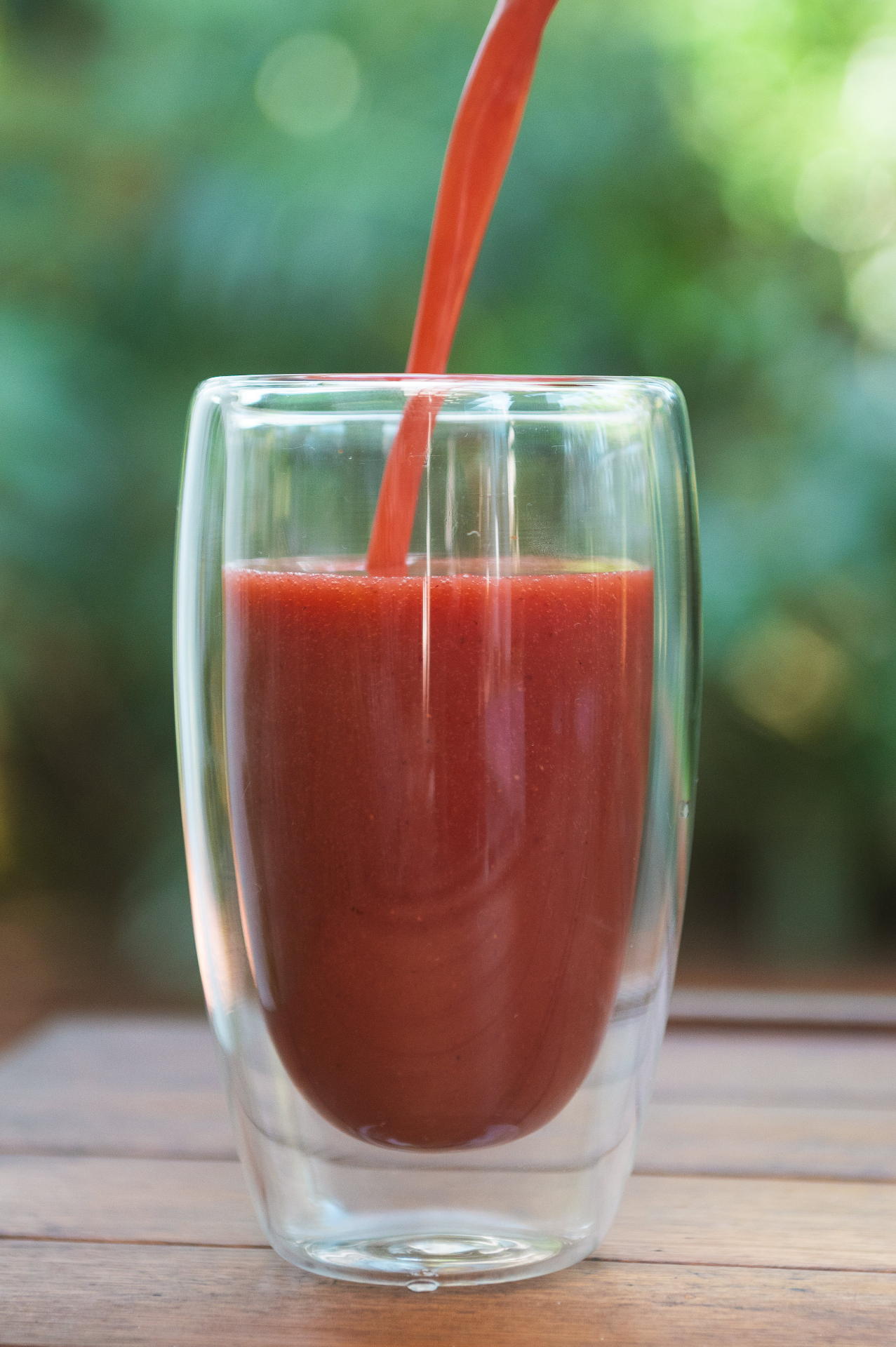 Suco vermelho sendo servido em copo de vidro