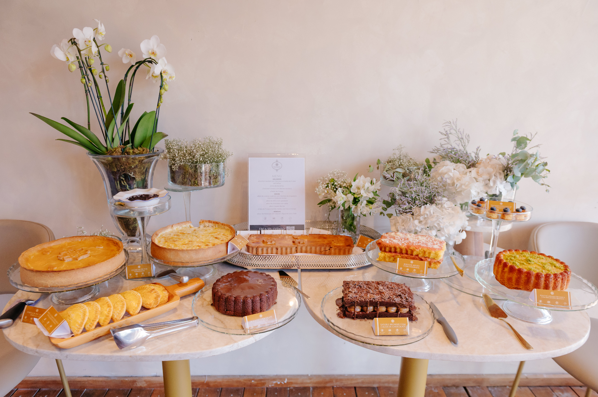 Mesa de evento com tortas, bolos, doces e arranjos florais da Move Gourmet
